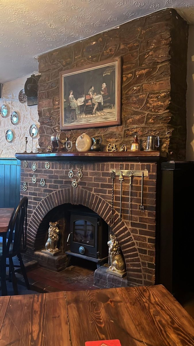 Brick fireplace with crowned gold lions and horse brasses in the bar